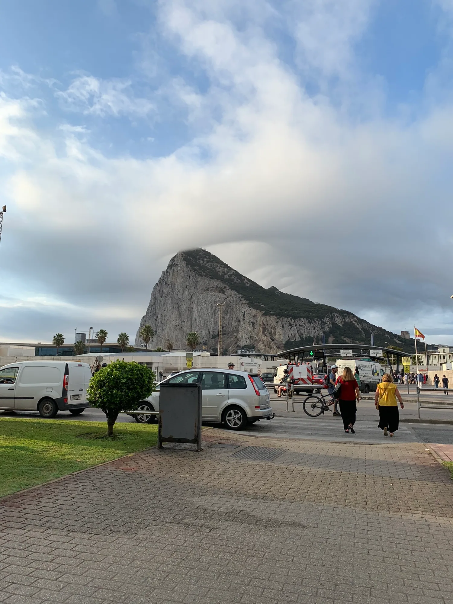 Pedestrians crossing the frontier plaza toward the cloud-capped Rock of Gibraltar