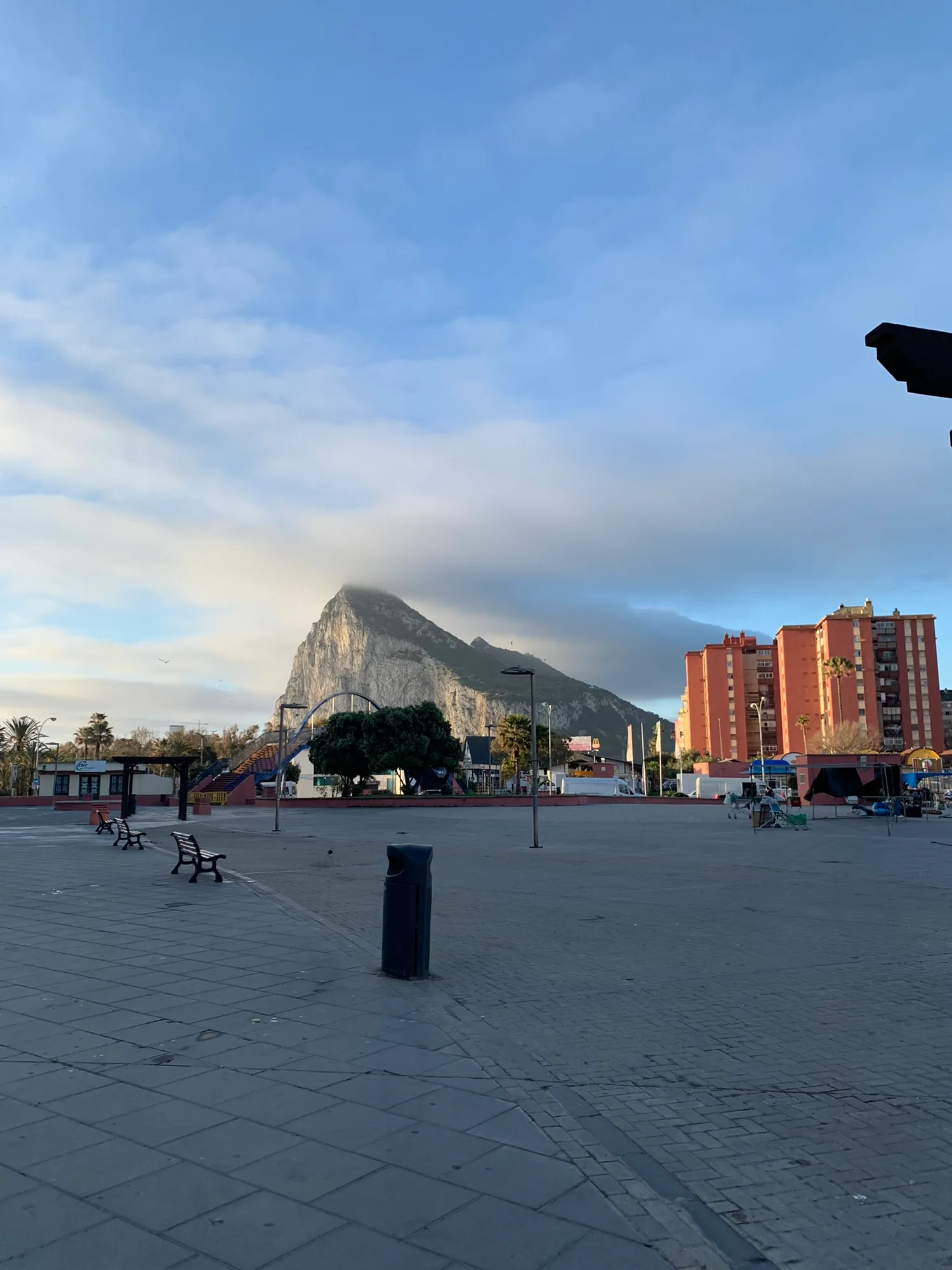 The empty frontier plaza in La Linea on a winter morning, benches and a playground in front of the Rock of Gibraltar.