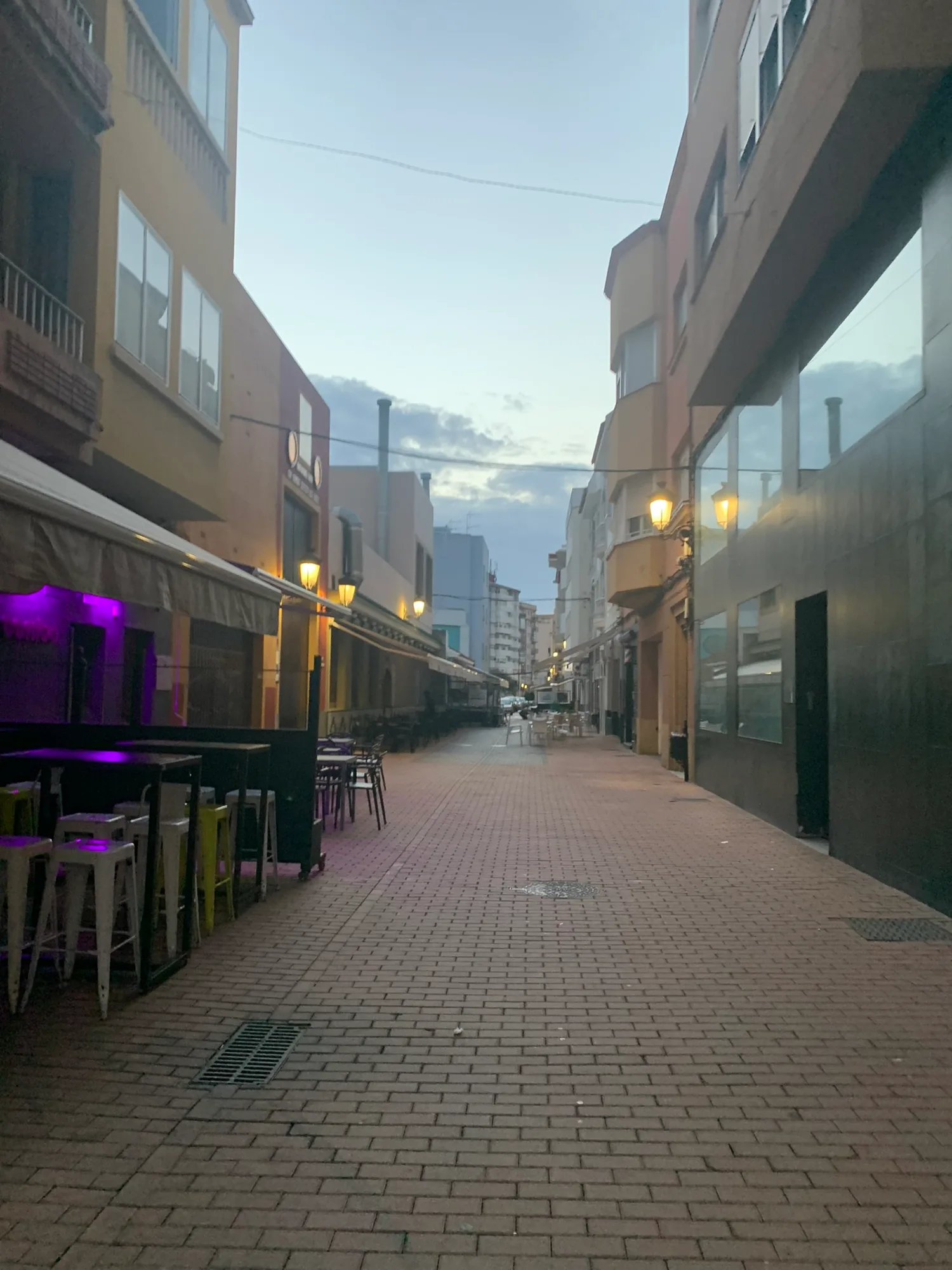 A La Linea bar street at night, stools under purple neon.