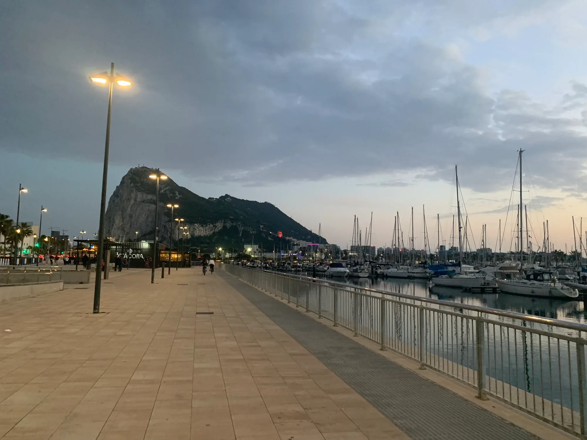 La Línea marina and seafront promenade at dusk with the Rock of Gibraltar behind