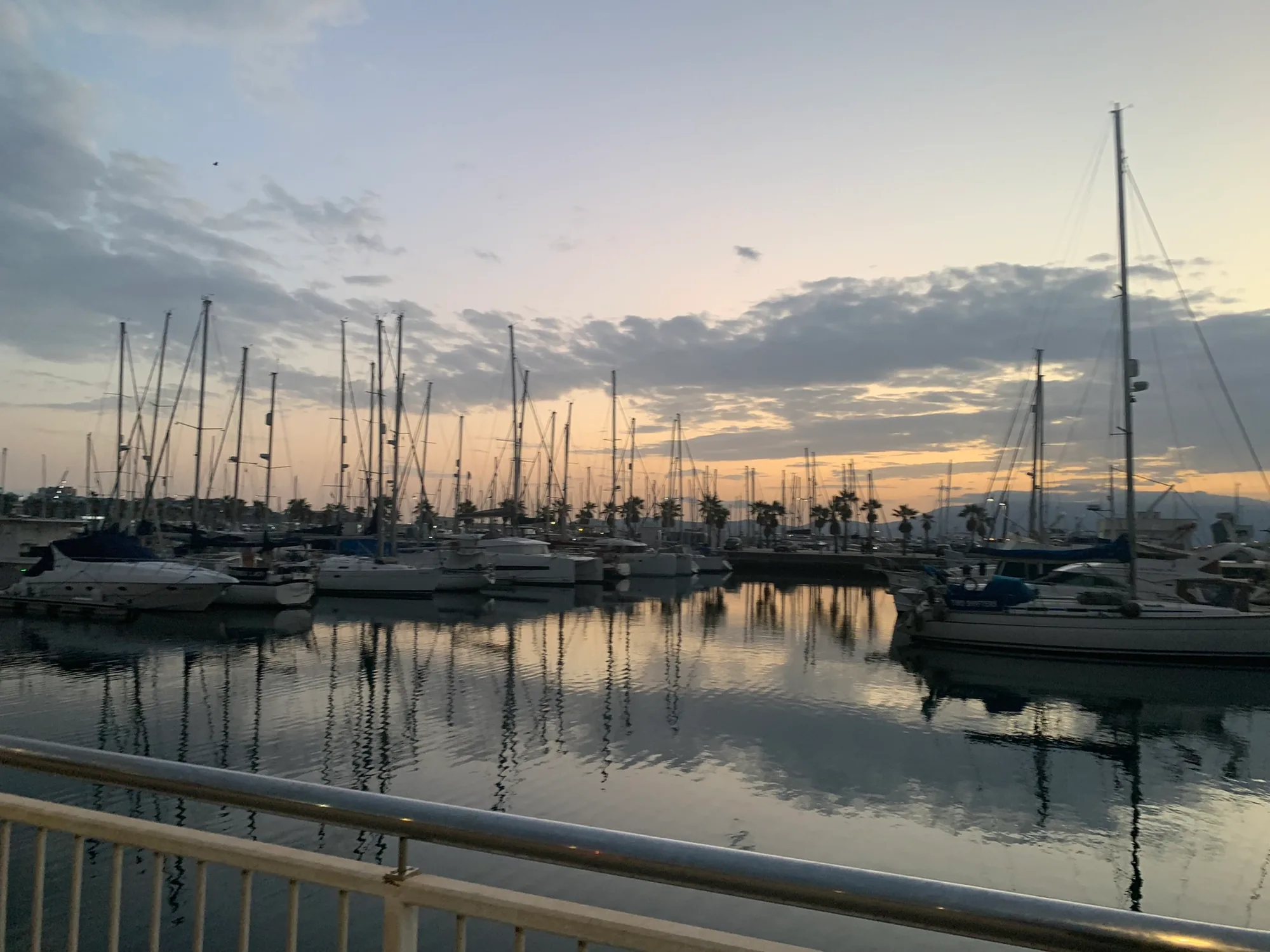 The marina at La Linea at sunset, moored boats reflected in still water.