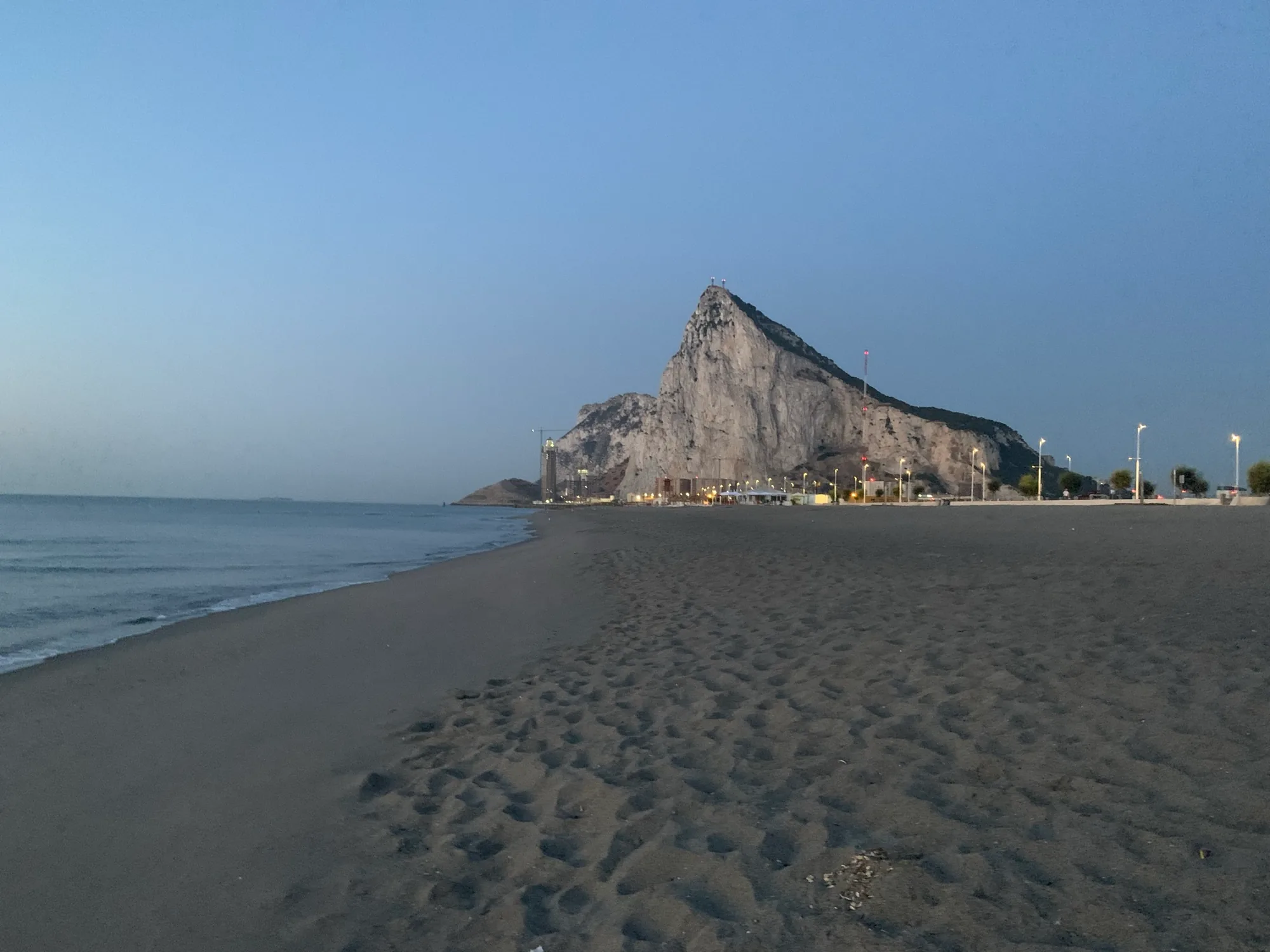 An empty Playa de Levante at sunrise, with the Rock of Gibraltar behind.