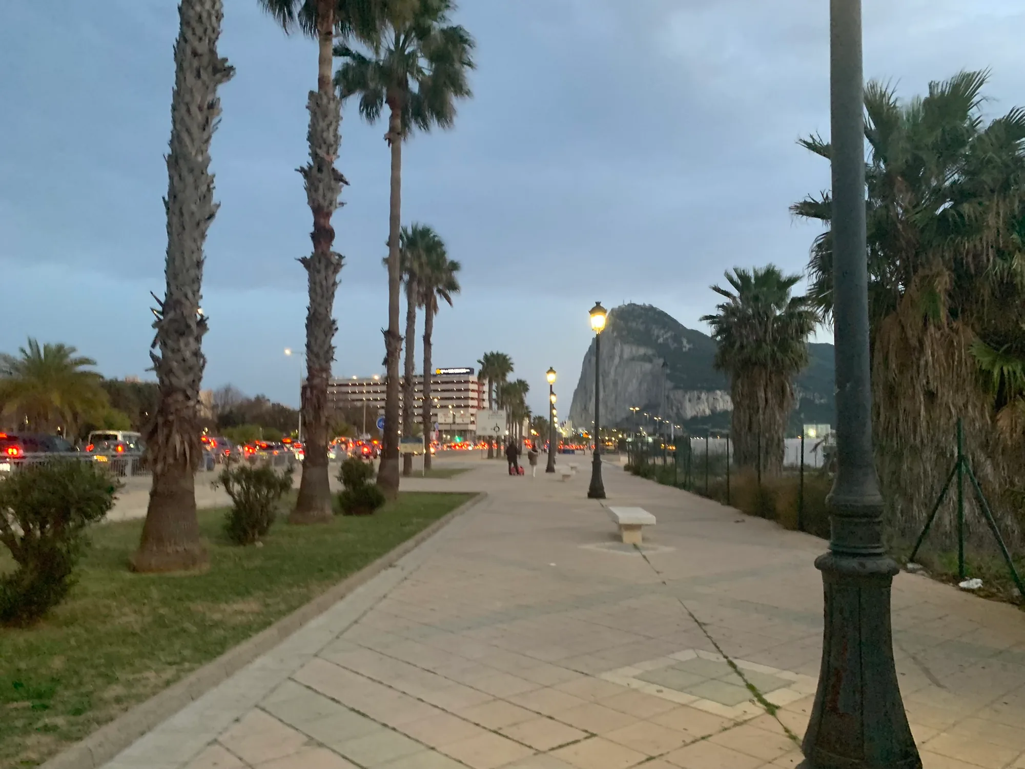 The Paseo Maritimo at dusk, palms lining the walk and the Rock of Gibraltar beyond.