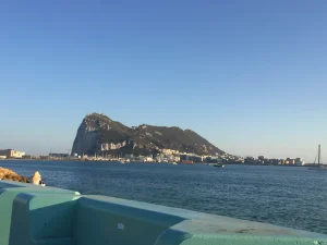 The Rock of Gibraltar across the bay from a turquoise seawall in La Línea