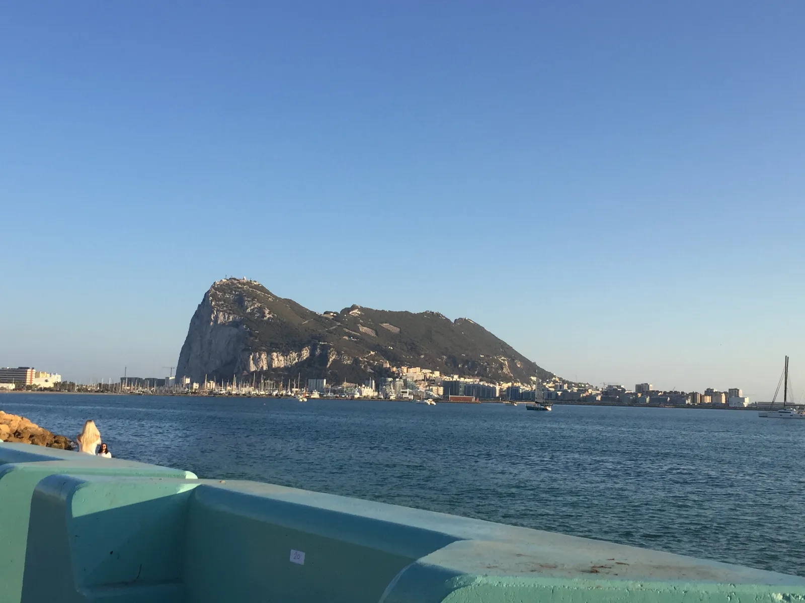 The Rock of Gibraltar across the bay from a turquoise seawall in La Línea